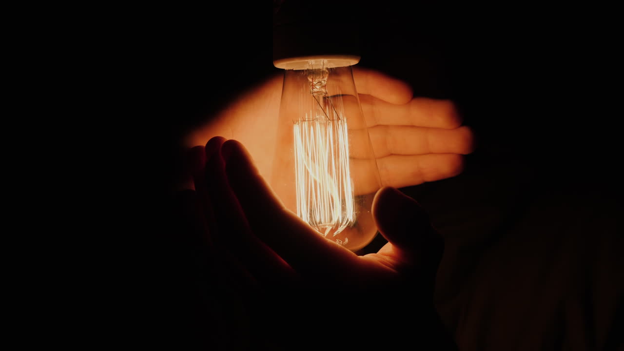 한 남자가 전구 주위에 손을 잡고 있다