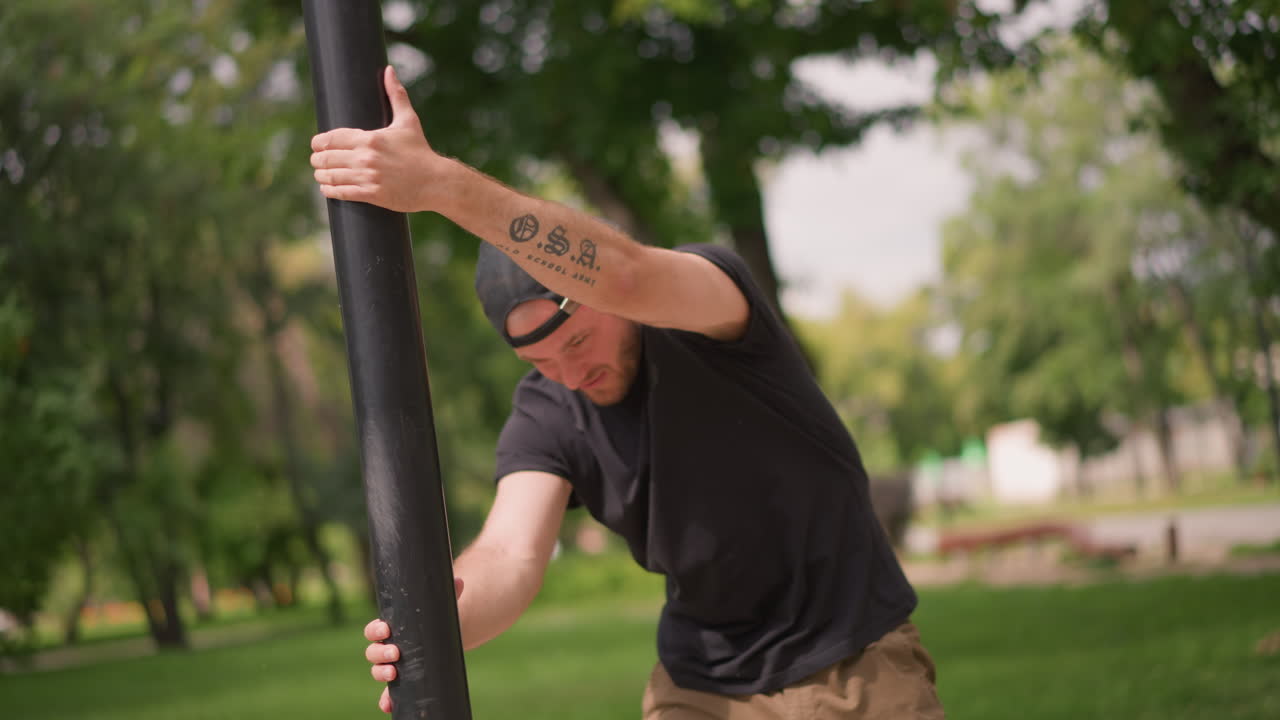 Tough Man In Nature, Tattooed Individual Performing Calisthenics Outside Amid Greenery, Determined Athletic Person With Tattoos Engaging In Outdoor Fitness Amidst Lush Park Scenery During Daylight