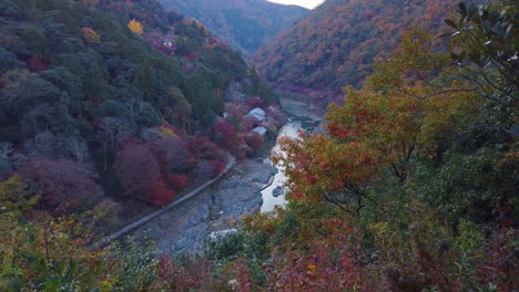 Arashiyama-in-Vibrant-autumn-color,-pan-up-reveal-mountains-mountains-and-river