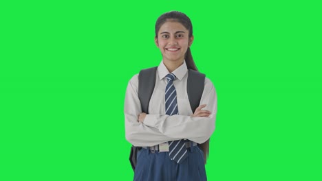 chica de la escuela india feliz de pie con las manos cruzadas pantalla verde