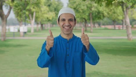 happy muslim man showing thumbs up in park