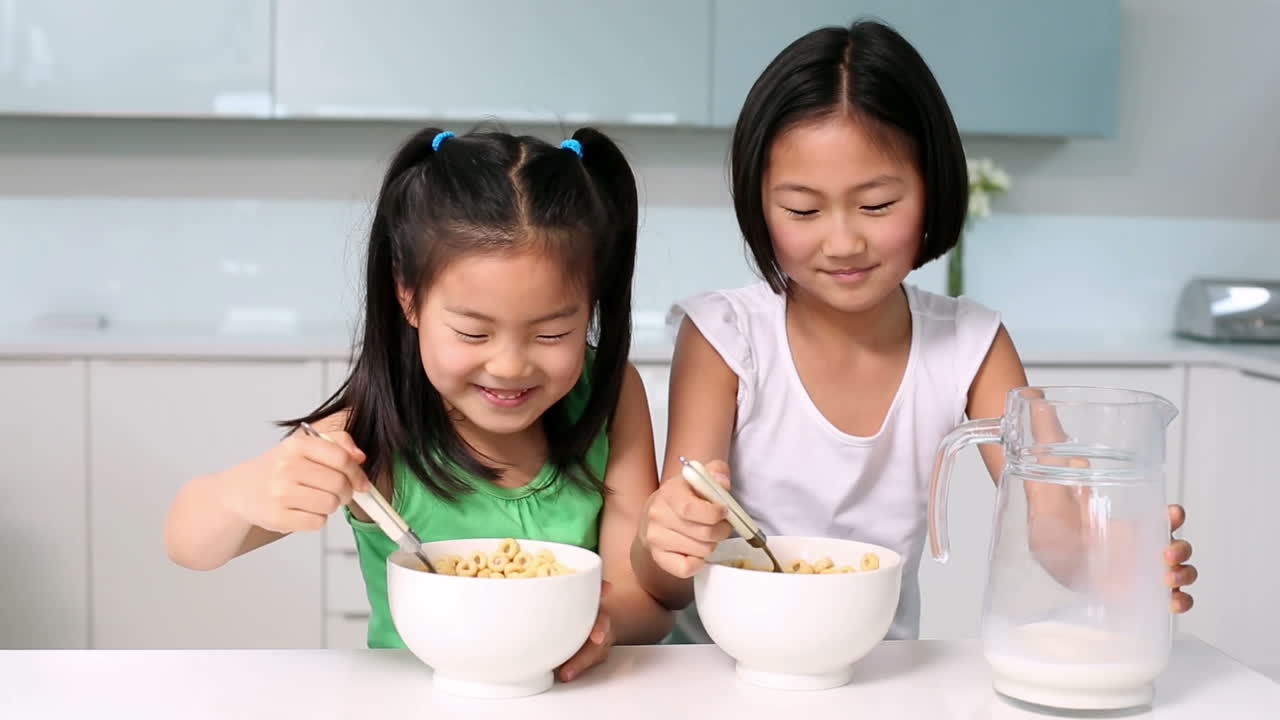 두 명의 행복한 소녀들이 시리얼을 먹고 있습니다.