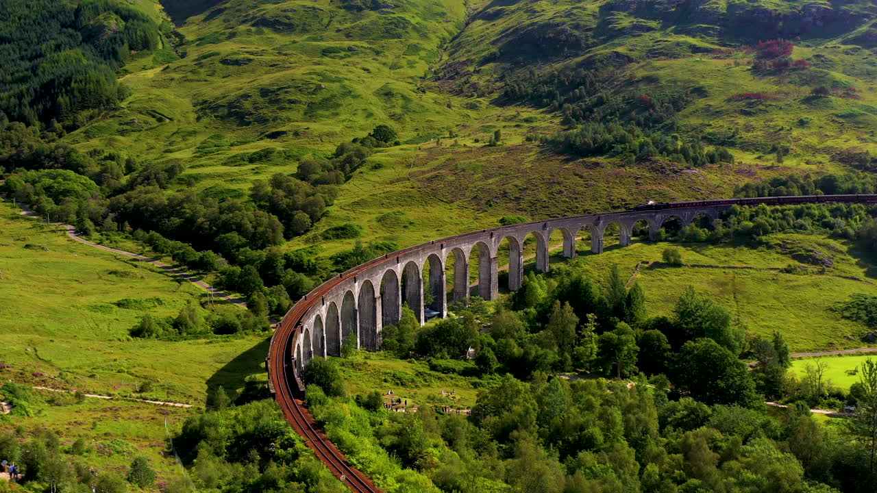 tiro de dron giratorio del famoso puente ferroviario en el viaducto de glenfinnan con tren en las vías