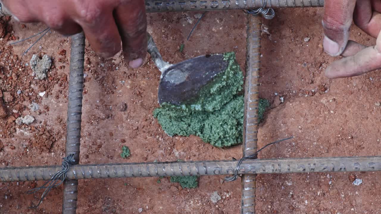Person filling Epoxy resin adhesive in rock hole to fix Rebar Anchoring in footing work at construction site, day time, stable shot, 4k