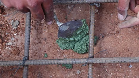 person filling epoxy resin adhesive in rock hole to fix rebar anchoring in footing work at construction site, day time, stable shot, 4k