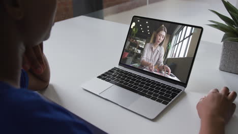 sección media de una mujer afroamericana haciendo una videollamada en una computadora portátil con una colega en la oficina