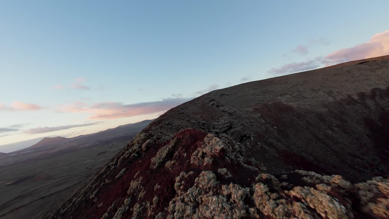 FPV drone flight over peak of Volcano Calderón Hondo in Fuerteventura. Sunset time and flight into crater hole. Cinematic drone shot.