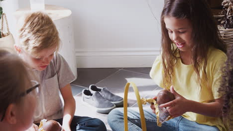 Group-Of-Children-Sitting-On-Floor-At-Home-Eating-Chocolate-Eggs-They-Have-Found-On-Easter-Egg-Hunt