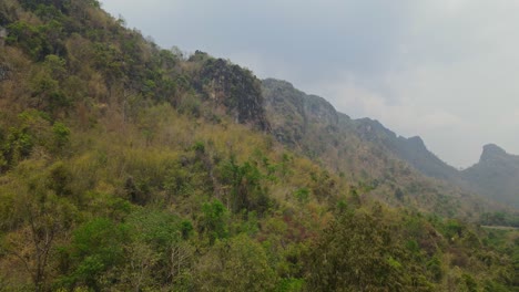 4k aerial reverse footage of a natural landscape of an unspoiled tranquil forest environment covered by limestone cliffs and mountains in a remote area of thailand southeast asia