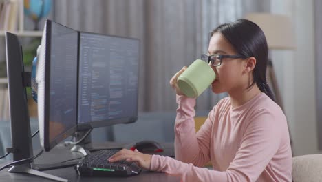 programatora adolescente asiática bebiendo agua mientras crea ingeniero de software desarrollando aplicación, programa, videojuego en casa en la computadora de escritorio en casa. terminal con lenguaje de codificación