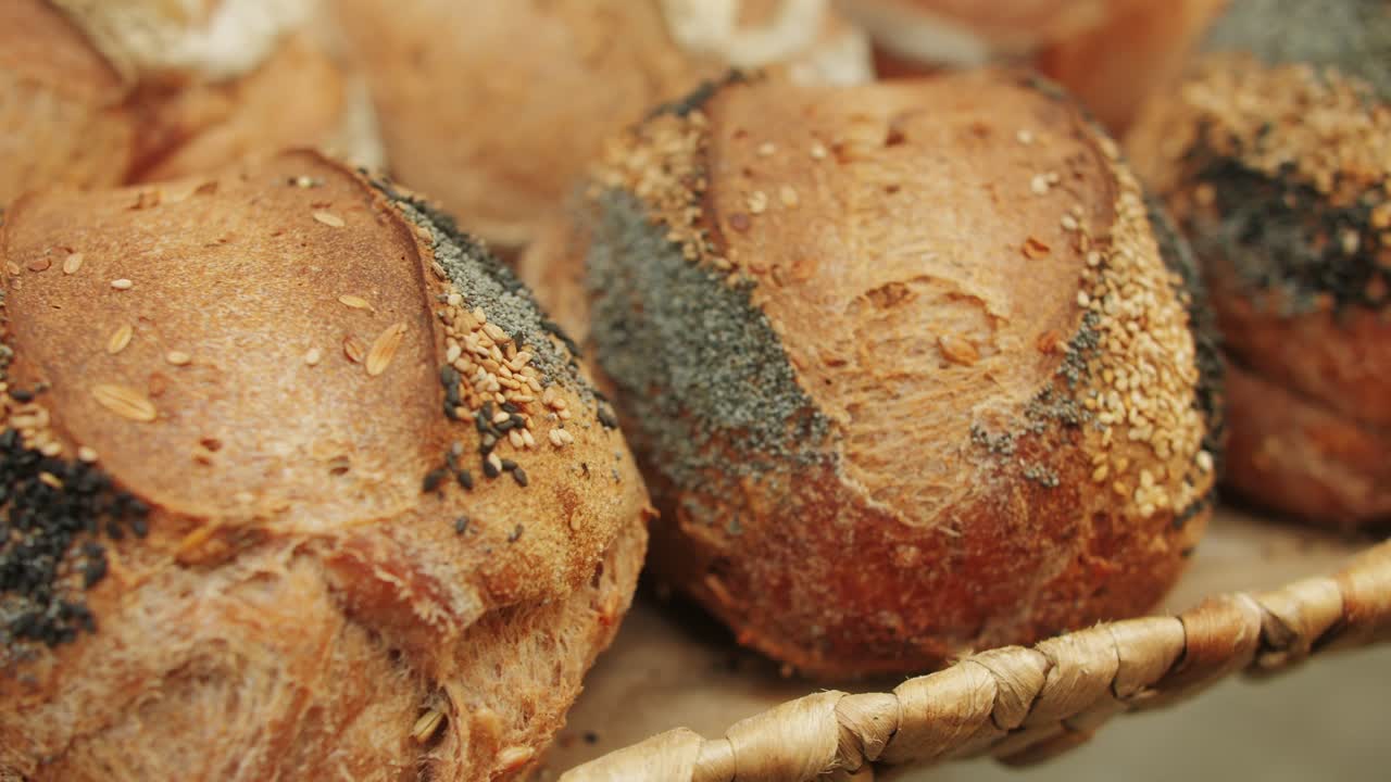 The baker holds in hands a of fresh bread with black poppy garnish on top close-up. Artisan bread is making by skill bakers using natural and high-quality ingredients. Food with health and flavour benefits.