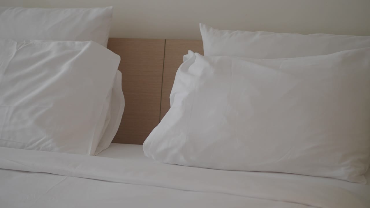 Un primo piano di un letto con cuscini e lenzuola bianchi