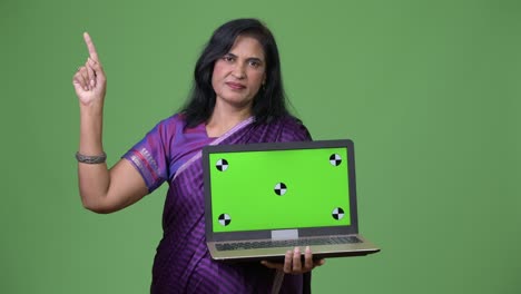 mature beautiful indian woman showing laptop and pointing up