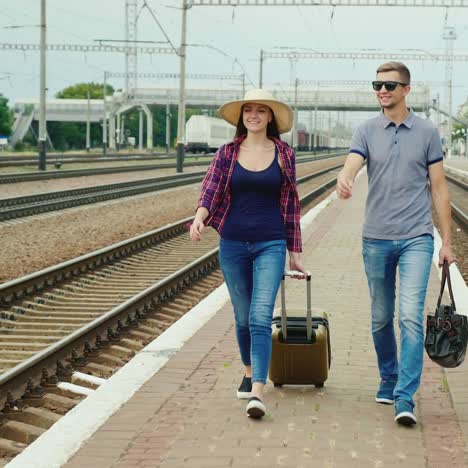 Una-Pareja-Joven-Con-Maletas-Sube-Al-Andén-De-La-Estación-1