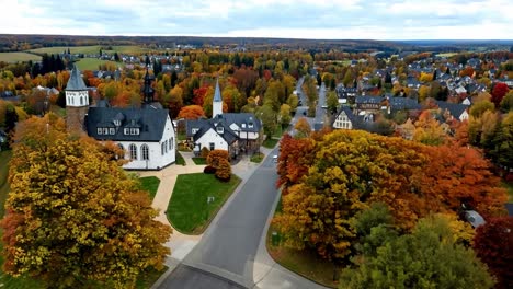 aerial view of a small town in germany with a church and fall foliage