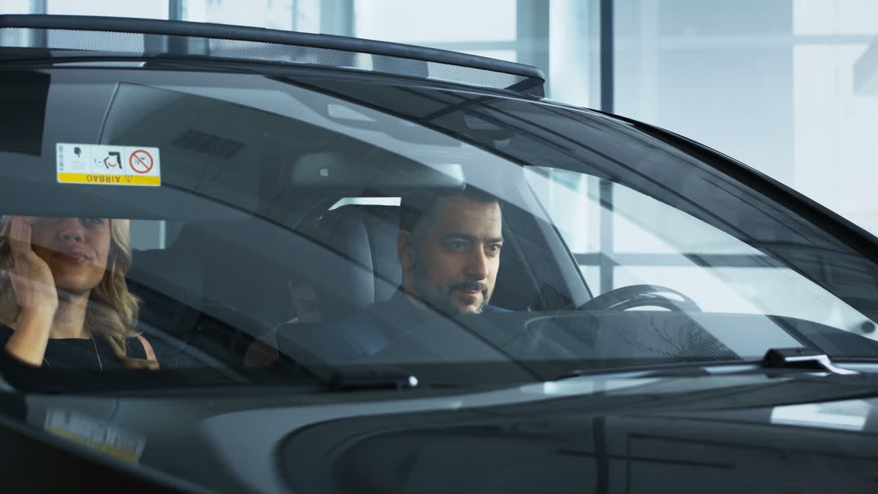 una pareja mirando un coche nuevo en una sala de exposiciones