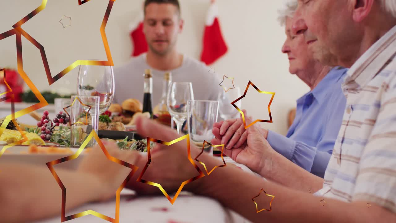 크리스마스 저녁 식사 전에 기도하는 산타 모자를 가진 카우카시안 가족 위의 별의 애니메이션