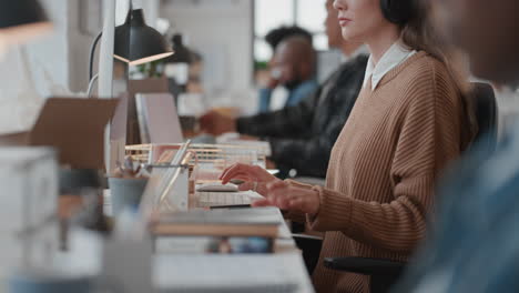 Mujer-De-Negocios-Joven-Que-Usa-Una-Computadora-Escribiendo-Correos-Electrónicos-Trabajando-En-Un-Proyecto-En-Una-Oficina-Ocupada-Revisando-Mensajes-En-Un-Teléfono-Inteligente