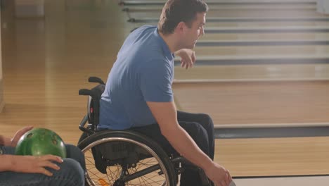 two young disabled men in wheelchairs playing bowling in the club