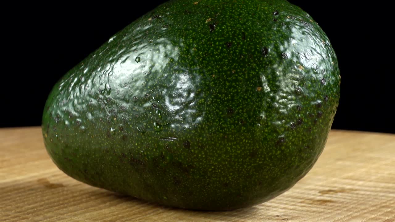 Avocado su sfondo nero. Tagliere in movimento.