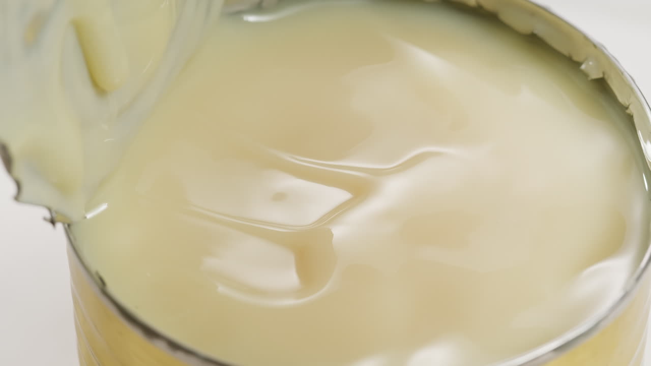 Tasty condensed milk, spoon and waffles on light grey table, flat lay. Space for text. High quality 4k footage