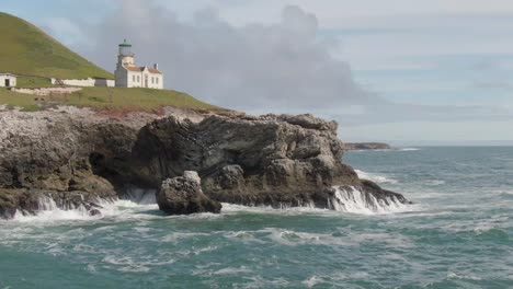 historic lighthouse on coastal cliffs, low drone orbit