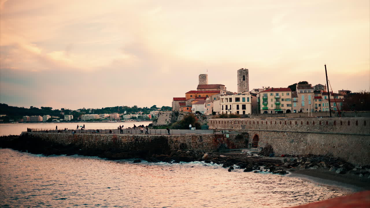 People walking on the coast in Antibes, France at sunset