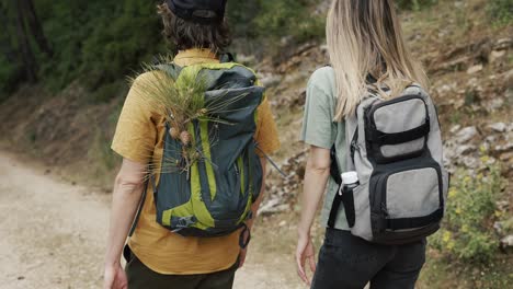 Unrecognizable-couple-backpackers-walking-by-forest's-rocky-path