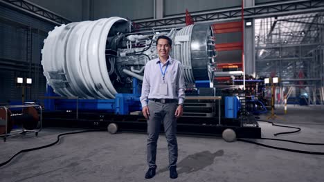 full body of an asian male professional worker standing with airplane engine maintenance conducted, analytics checking the turbine, he look at the camera and smiling