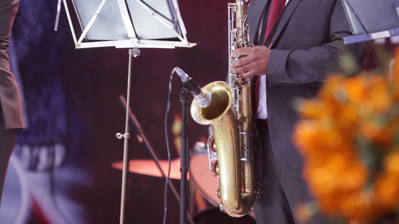 closeup of a male musician playing the saxophone to a microphone in a concert, scene lights and concert