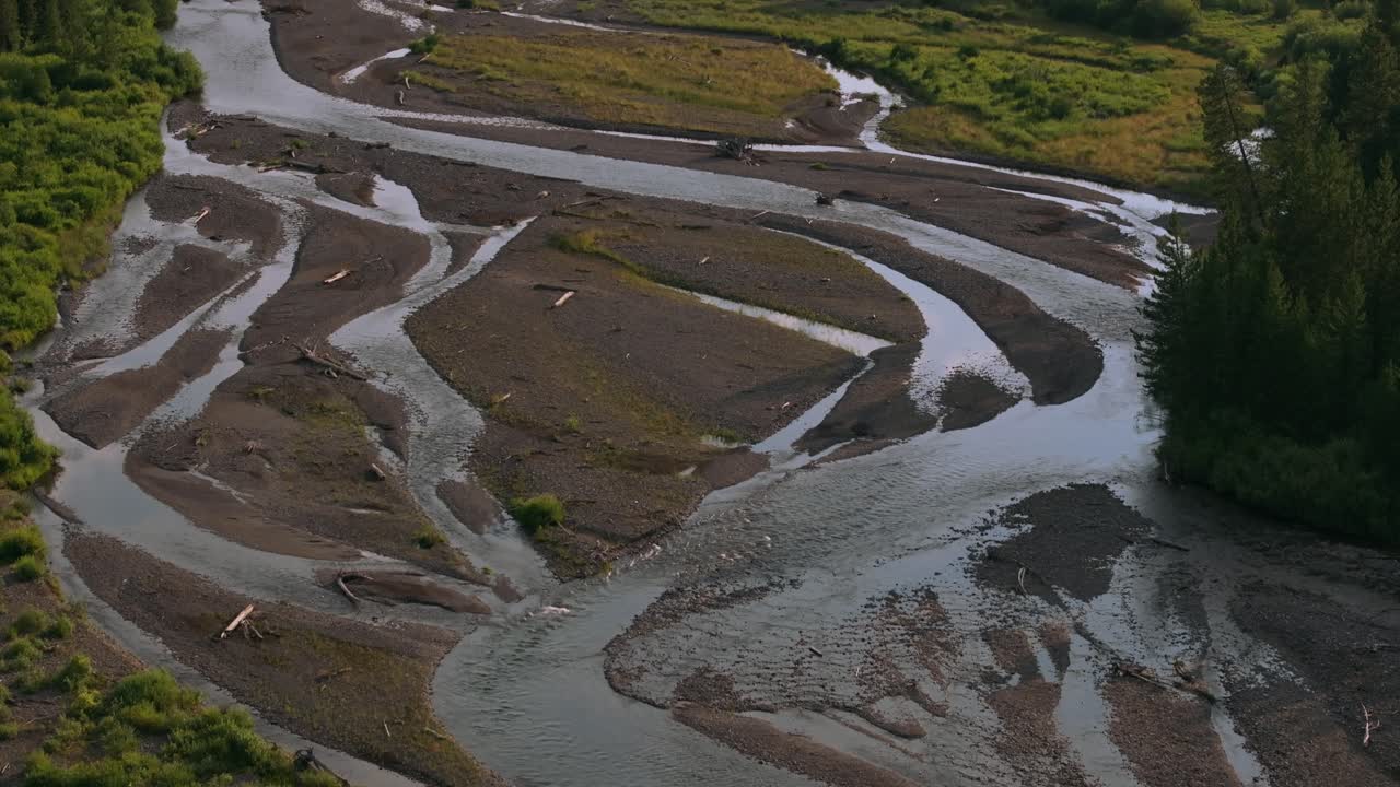 Aerial dolly over Sunlight Basin, Wyoming, revealing the winding meandering river, vast forest, and surrounding mountain peaks