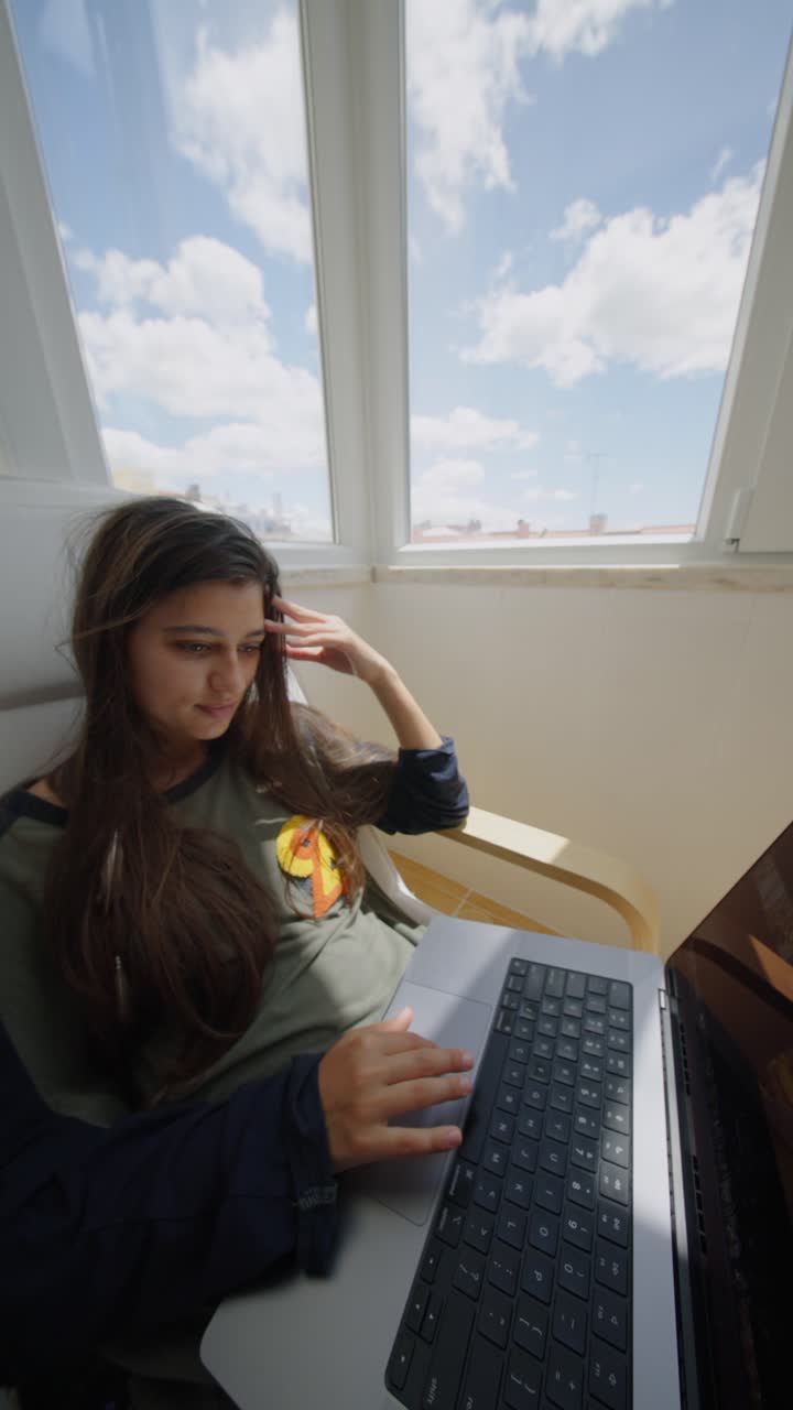 Woman working on laptop by window