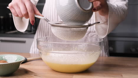 hands pouring all purpose flour into wire sieve