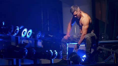 man pickup dumbell in gym. handsome muscular man working out with dumbbells