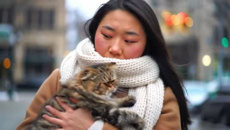 a heartwarming moment: a woman embraces her feline friend in a cozy winter setting, showcasing a deep bond against a charming urban backdrop