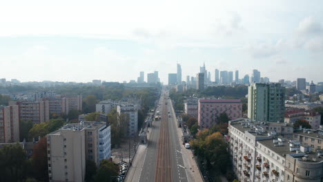 Vuela-Hacia-Atrás-Sobre-Un-Bulevar-Ancho-Y-Recto-En-La-Ciudad.-Carretera-De-Varios-Carriles-Y-Vía-De-Tranvía.-Horizonte-Con-Modernos-Edificios-De-Oficinas-De-Gran-Altura.-Varsovia,-Polonia