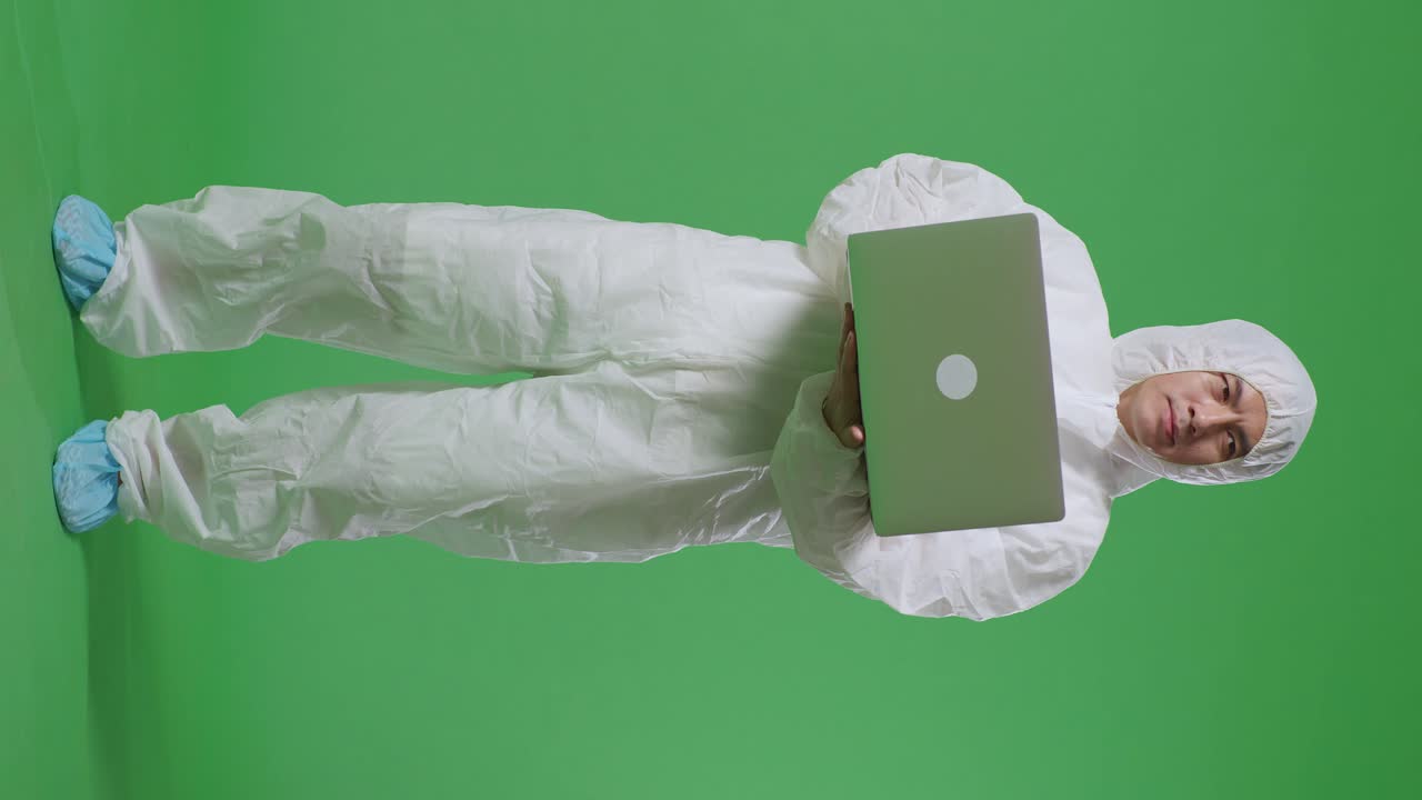 cuerpo lleno de científico masculino asiático escribiendo en una computadora portátil y mirando a su alrededor en el fondo de la pantalla verde