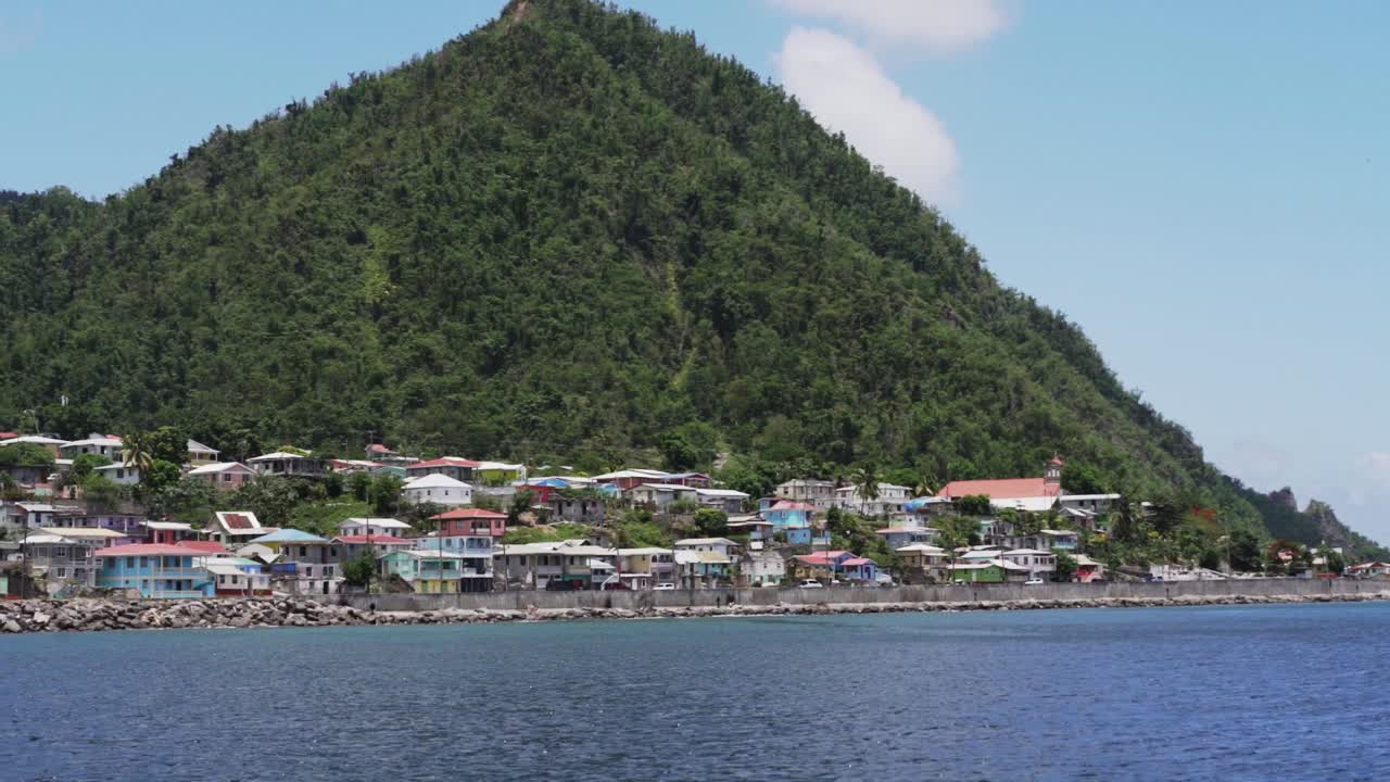 Large green hill on the coast of the Dominica, seascape with houses and green hills in the back