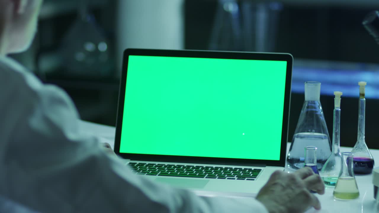 el científico está usando una computadora portátil con pantalla verde en el laboratorio. genial para el uso de maquetas.