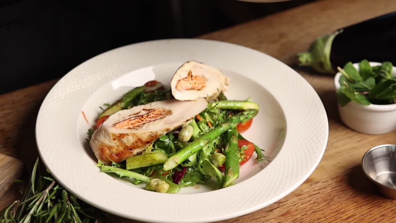 Chef che Impiattano un Rollè Gourmet di Pollo e Salmone con Insalata Fresca di Asparagi