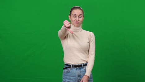 retrato de una joven insatisfecha mostrando el pulgar hacia abajo sacudiendo la cabeza no. disgustada hermosa mujer caucásica delgada posando en el fondo de la pantalla verde chromakey
