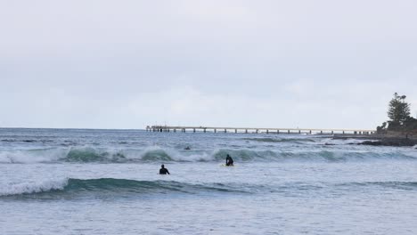 surfers catching waves near a scenic pier