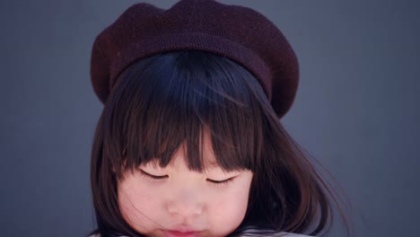 korean girl in a gray coat and cap stands the street in spring at the glass doors of the store