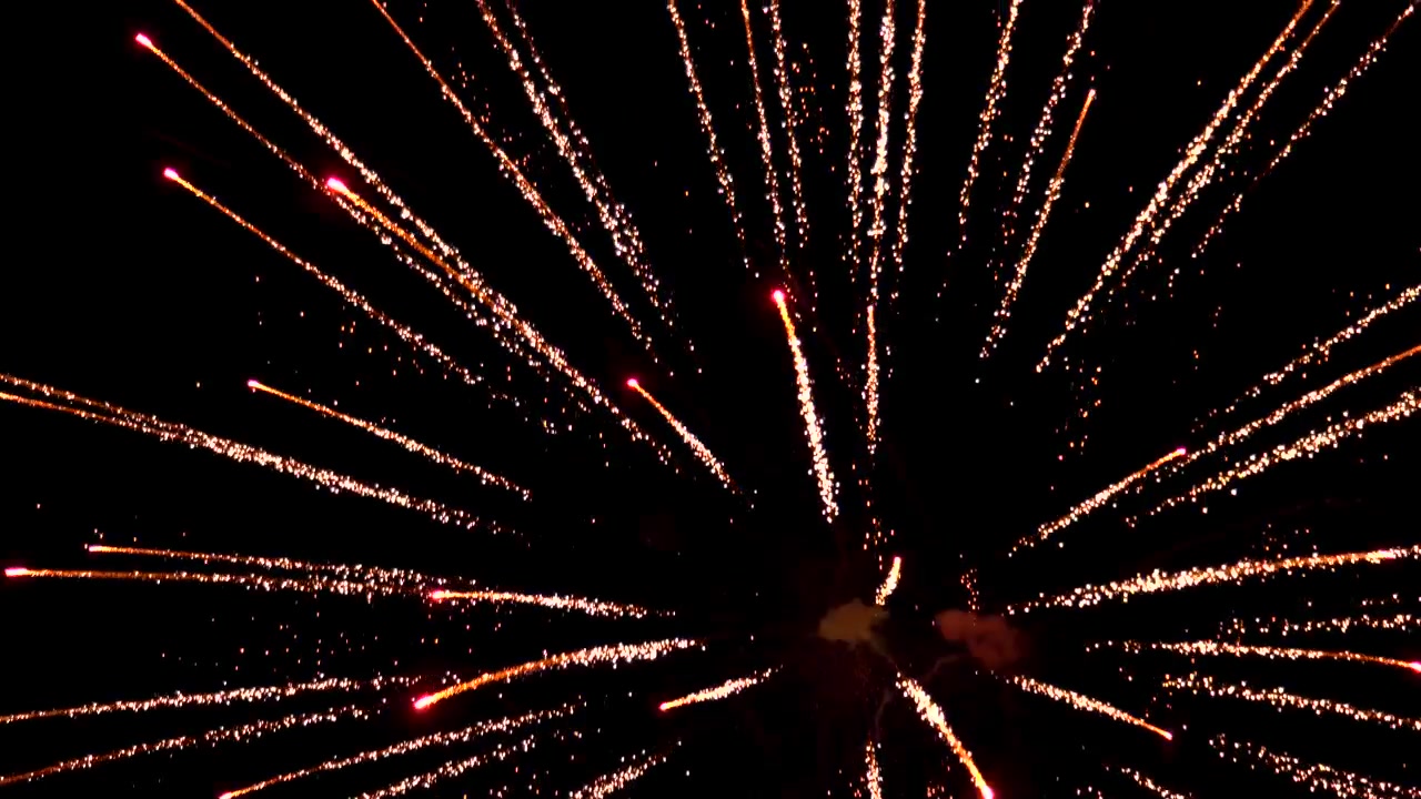Streaks of sparking golden light shoot across the night sky as pyrotechnics explode