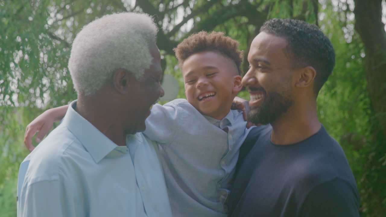 Smilende mandlig familie med flere generationer derhjemme i haven sammen.