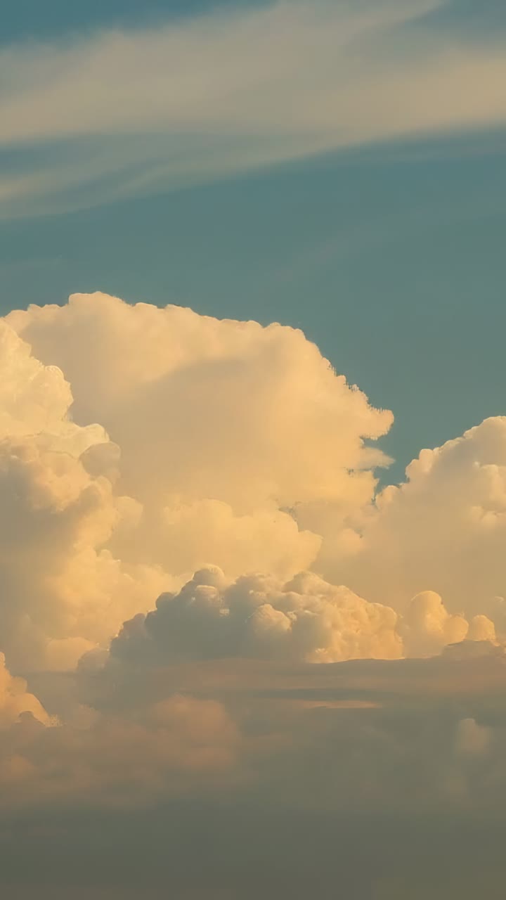 Vertical video: Reacting to shifting sunlight, cumulus clouds glowing over plain, with sunset glow
