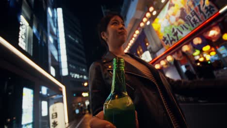 woman holding a bottle at night in tokyo