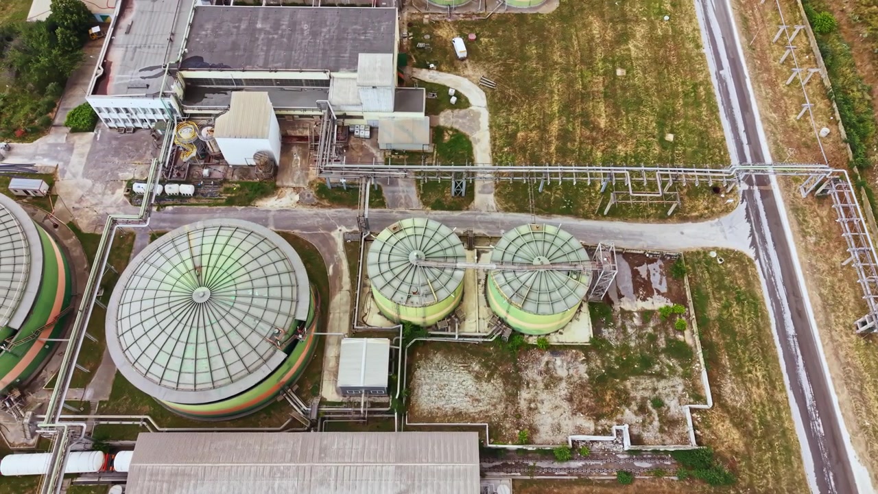 Industrial site with storage tanks and pathways near urban area during daytime