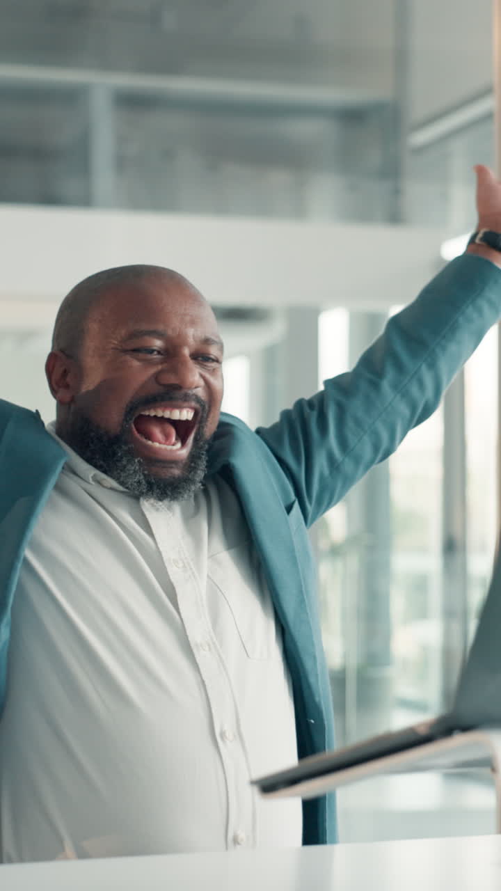 Blije zakenman viert succes terwijl hij op een laptop kijkt op kantoor