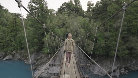 attractive european female tourist walking on suspension bridge at hokitika gorge